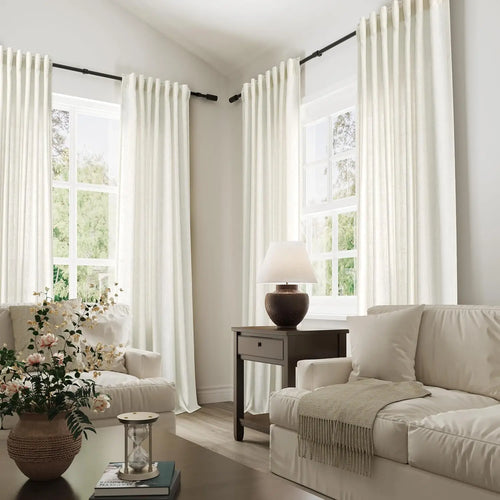 Ivory tall sheer curtains on black rods in a cream living room